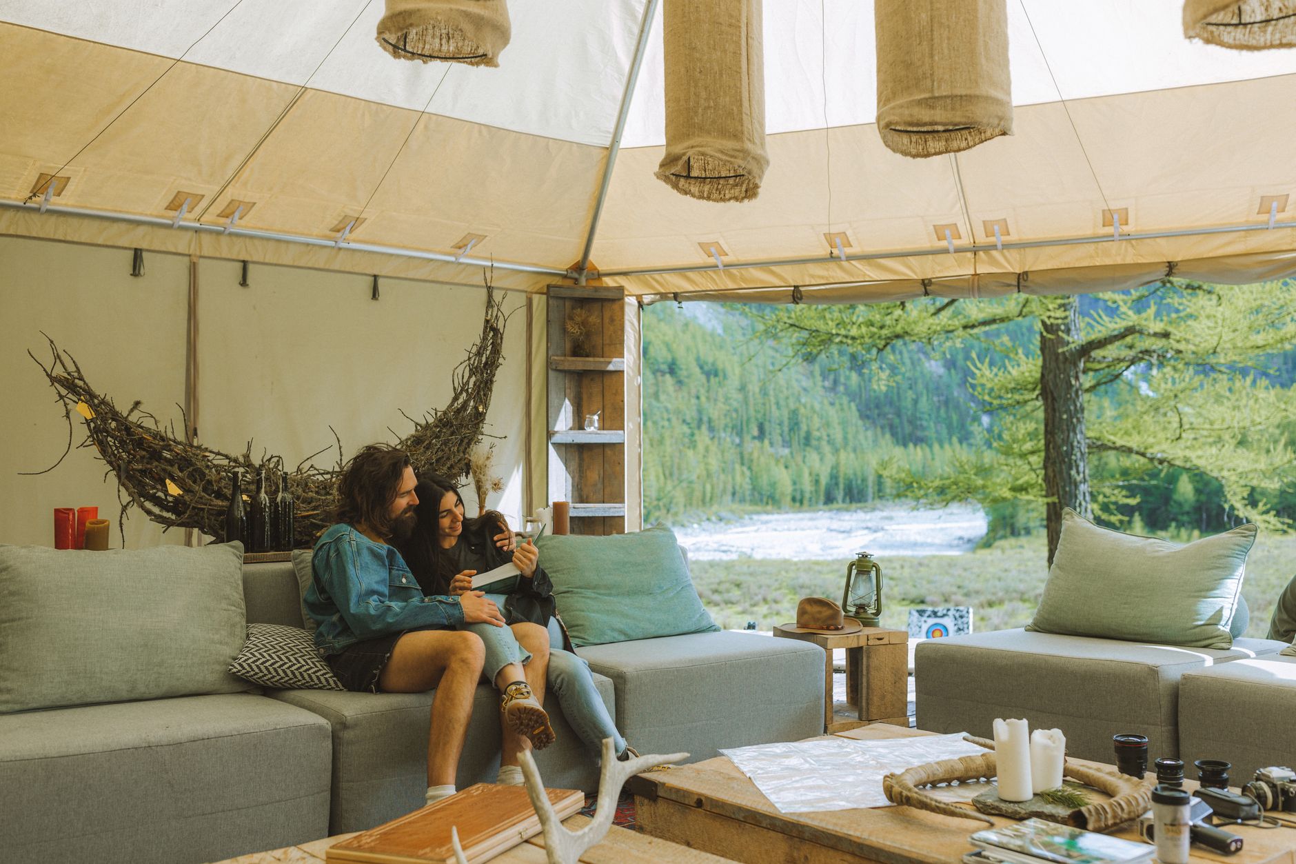 Tienda de glamping de lujo con cama y decoración cálida rodeada de bosque