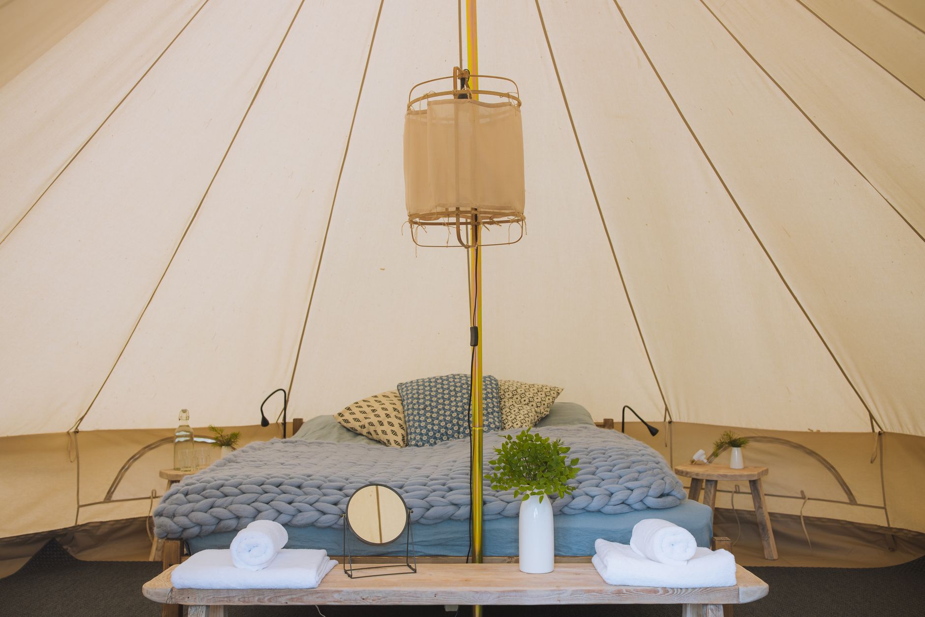 Stylish glamping tent featuring a cozy bed setup with rustic decor and natural lighting.